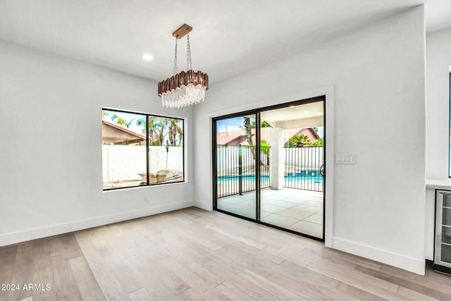 empty room with a chandelier and light hardwood / wood-style flooring