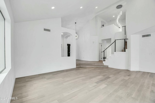 unfurnished living room with light wood-type flooring and high vaulted ceiling