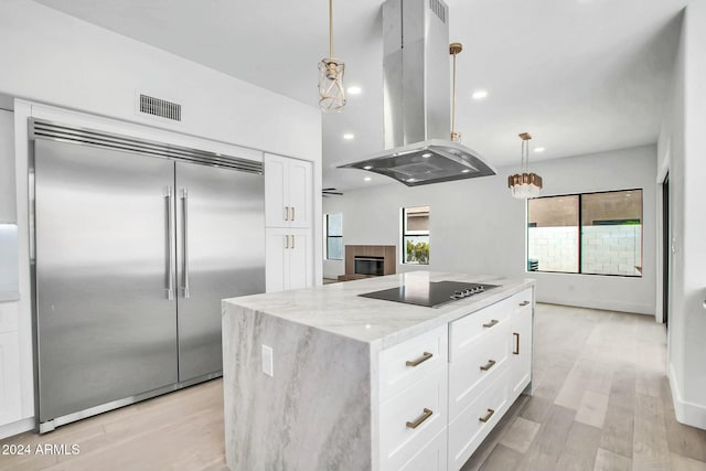 kitchen with pendant lighting, black electric stovetop, built in refrigerator, white cabinetry, and island exhaust hood