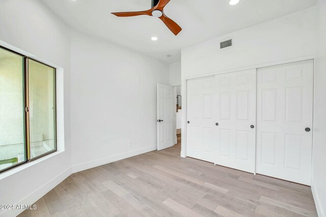 unfurnished bedroom with a closet, light hardwood / wood-style floors, and ceiling fan