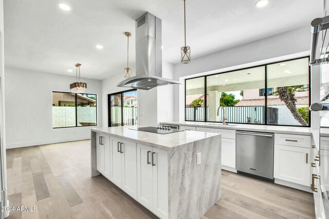 kitchen with island range hood, a kitchen island, white cabinetry, and a wealth of natural light