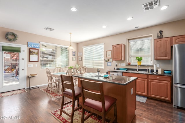 kitchen with a center island, decorative light fixtures, plenty of natural light, and appliances with stainless steel finishes