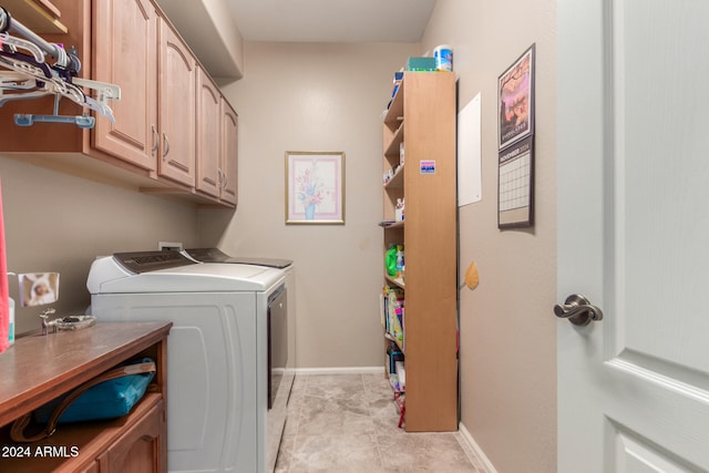 clothes washing area with cabinets, light tile patterned floors, and washer and dryer