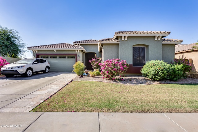 mediterranean / spanish home featuring a garage and a front yard