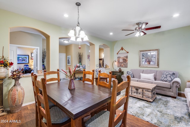 dining space with ceiling fan with notable chandelier and dark wood-type flooring