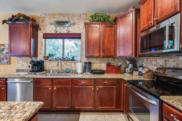 kitchen with light stone countertops, sink, appliances with stainless steel finishes, light tile patterned floors, and backsplash