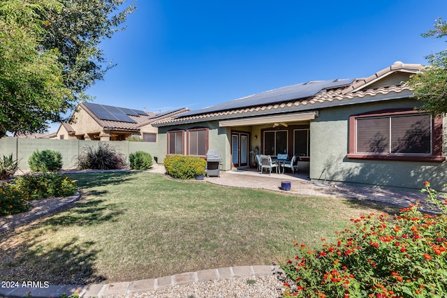 rear view of house featuring a lawn, a patio area, and solar panels