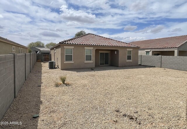 rear view of property with a fenced backyard, central air condition unit, stucco siding, and a tiled roof