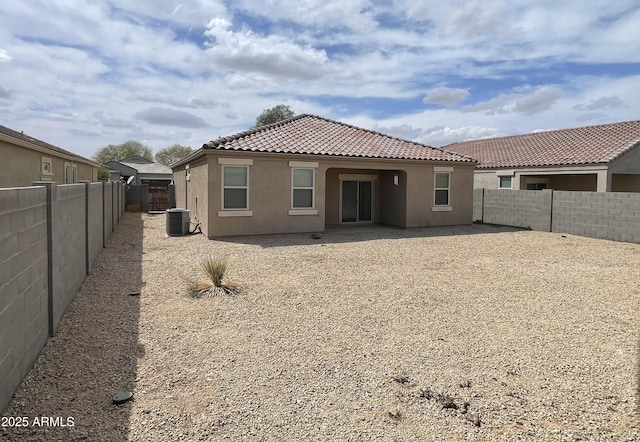 back of property featuring a fenced backyard, stucco siding, a tiled roof, and central AC unit