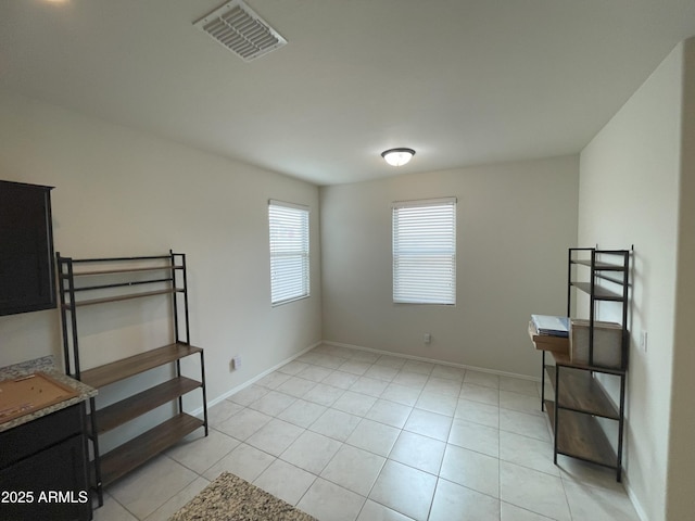 spare room with light tile patterned flooring, baseboards, and visible vents