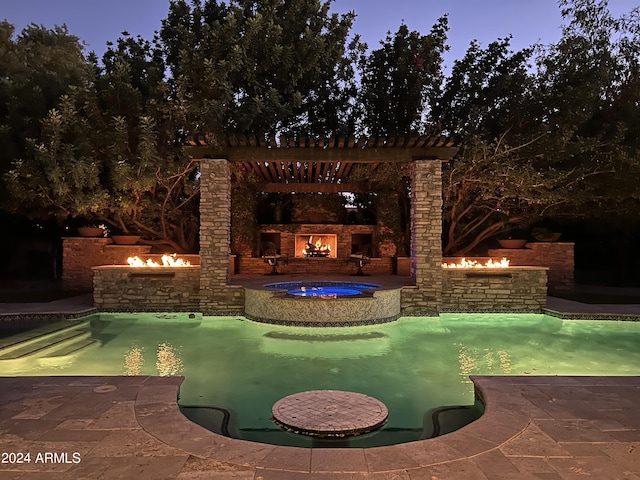 pool at dusk with a patio area and an in ground hot tub