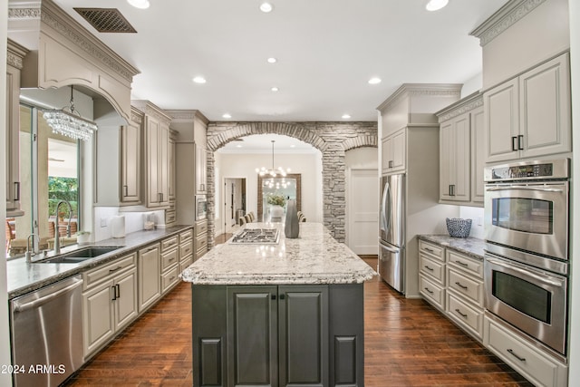 kitchen featuring a center island, appliances with stainless steel finishes, dark wood-type flooring, and sink