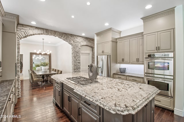 kitchen with dark hardwood / wood-style floors, a center island, ornamental molding, and appliances with stainless steel finishes