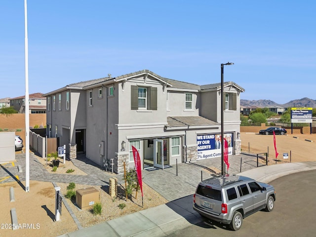 view of front of home featuring a tile roof, a mountain view, stone siding, and stucco siding