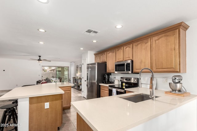 kitchen featuring light tile patterned flooring, a breakfast bar, sink, a kitchen island, and stainless steel appliances