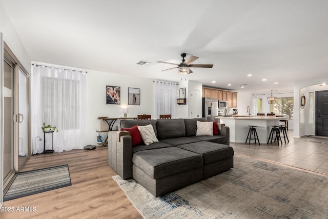 living room with sink, light hardwood / wood-style flooring, and ceiling fan