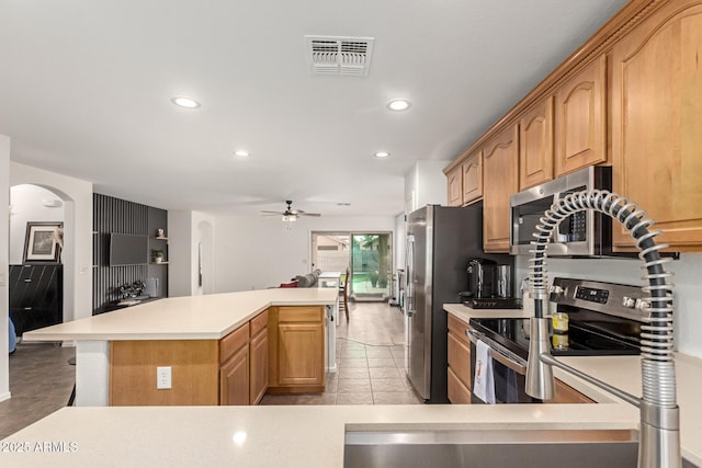 kitchen with ceiling fan, stainless steel appliances, and a kitchen island