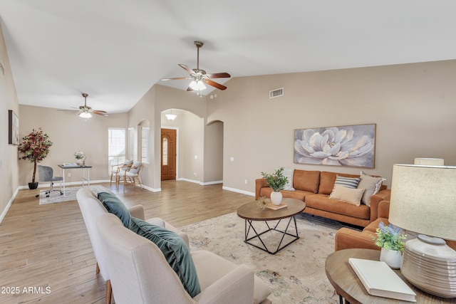 living room with ceiling fan, high vaulted ceiling, and light wood-type flooring