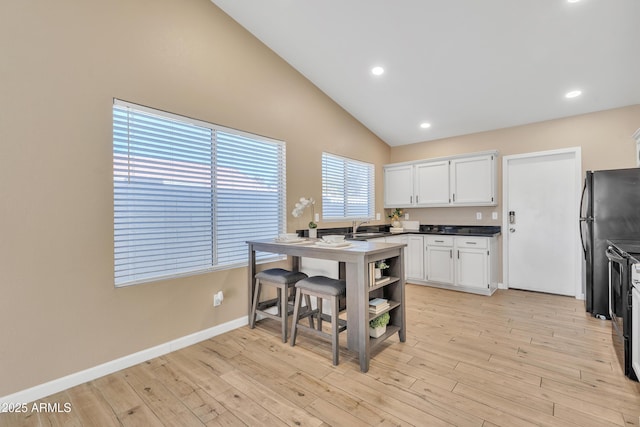 kitchen with sink, vaulted ceiling, light hardwood / wood-style floors, and white cabinets