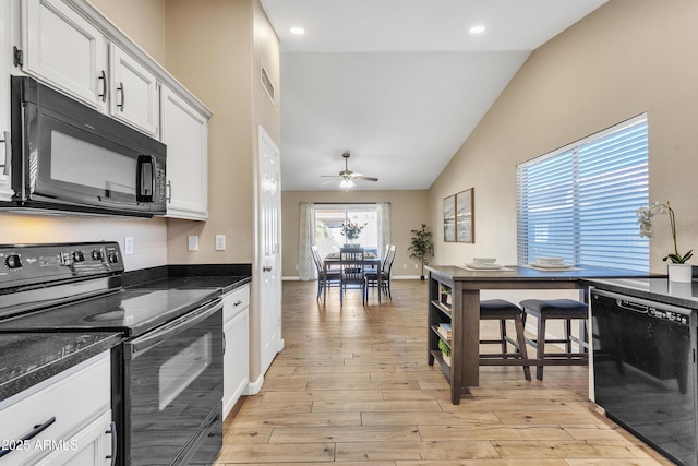 kitchen featuring white cabinets, dark stone countertops, light wood-type flooring, and black appliances