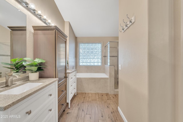 bathroom with hardwood / wood-style flooring, lofted ceiling, vanity, and independent shower and bath