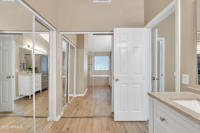 bathroom featuring hardwood / wood-style flooring, vanity, and tiled tub