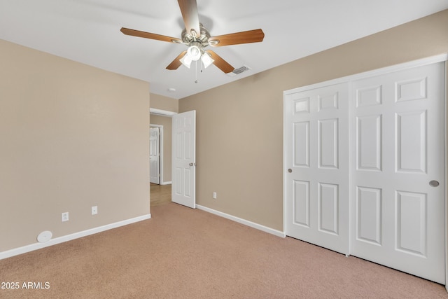 unfurnished bedroom with light carpet, ceiling fan, and a closet