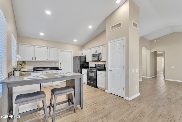 kitchen featuring white cabinetry, black appliances, kitchen peninsula, and a kitchen bar