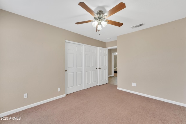 unfurnished bedroom featuring light carpet, a closet, and ceiling fan