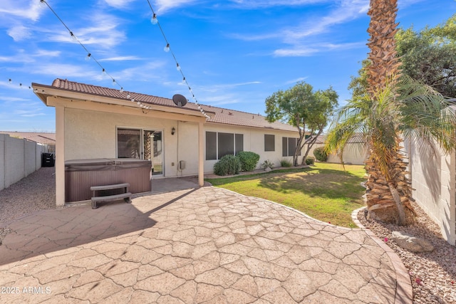 back of house with a patio area, a hot tub, and a lawn