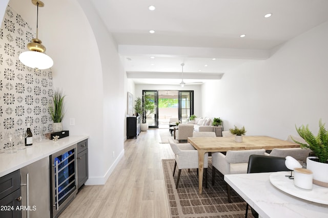 dining space with light hardwood / wood-style floors, beverage cooler, and indoor bar