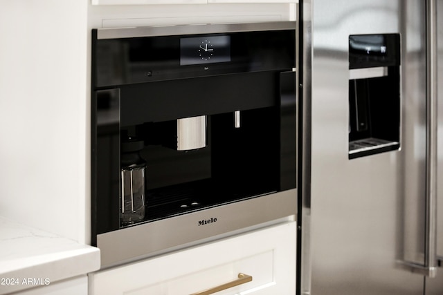 details featuring light stone counters, white cabinets, and oven