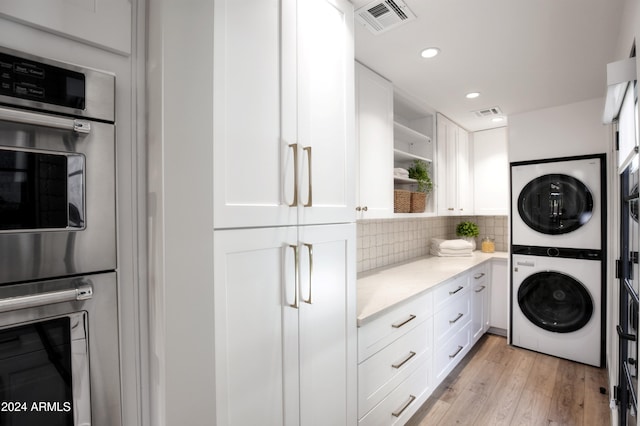 washroom featuring light hardwood / wood-style floors and stacked washer / dryer