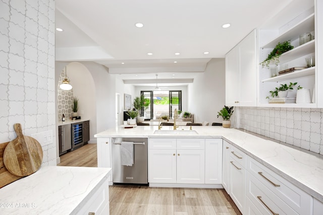 kitchen with light wood-type flooring, white cabinetry, light stone counters, and sink