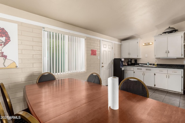 dining area with light tile patterned floors and brick wall