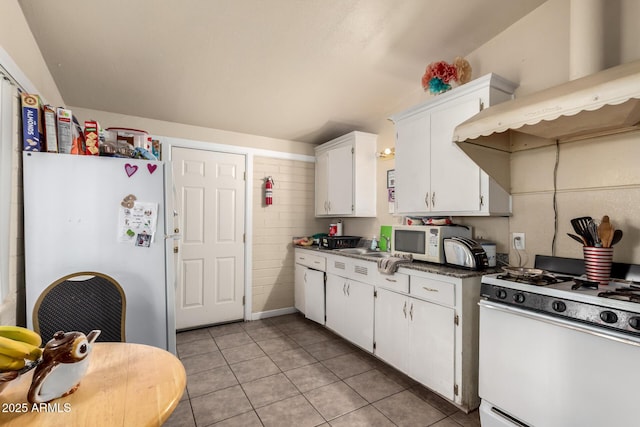 kitchen featuring dark countertops, white cabinetry, white appliances, exhaust hood, and light tile patterned floors