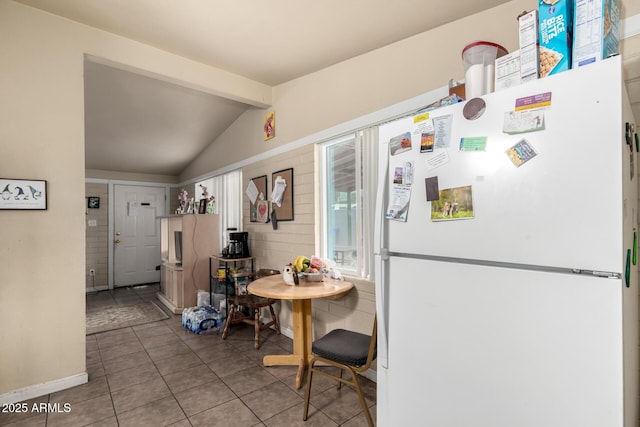 kitchen featuring tile patterned flooring, lofted ceiling with beams, and freestanding refrigerator