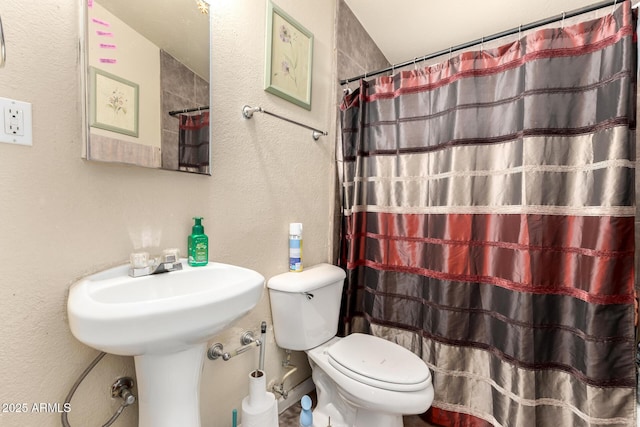 full bath featuring curtained shower, toilet, and a textured wall