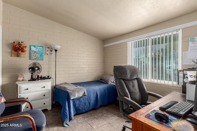 bedroom with light tile patterned floors, brick wall, and lofted ceiling