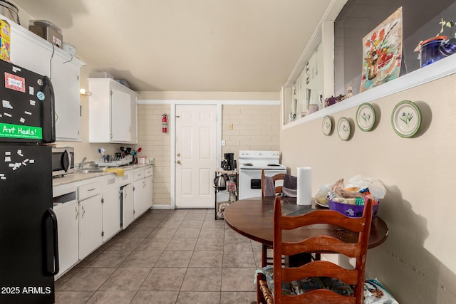 kitchen featuring white range with electric cooktop, light tile patterned flooring, freestanding refrigerator, light countertops, and stainless steel microwave