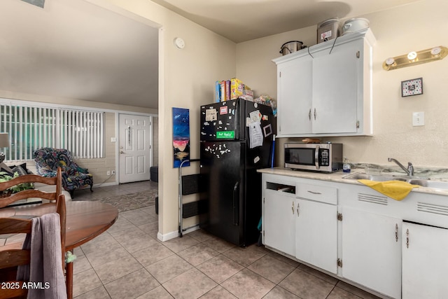 kitchen with freestanding refrigerator, a sink, light countertops, white cabinets, and stainless steel microwave