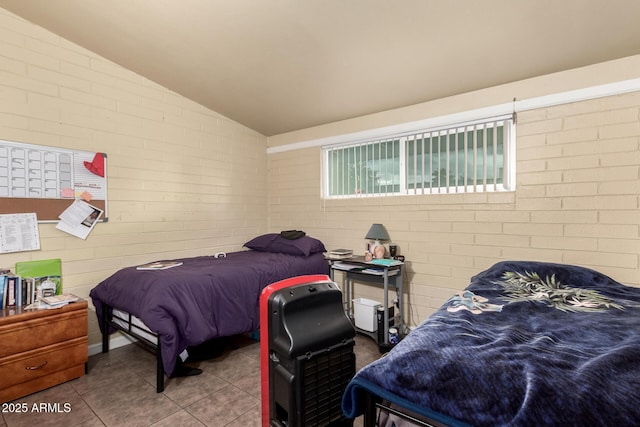 tiled bedroom featuring brick wall and vaulted ceiling