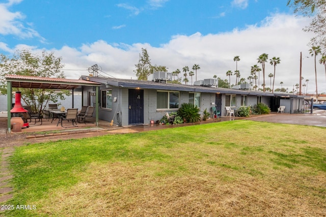 back of house with metal roof, a patio, and a lawn