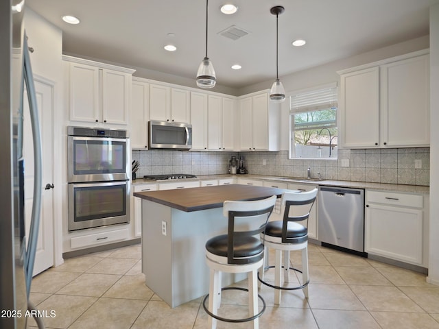 kitchen with stainless steel appliances, a center island, pendant lighting, and white cabinets