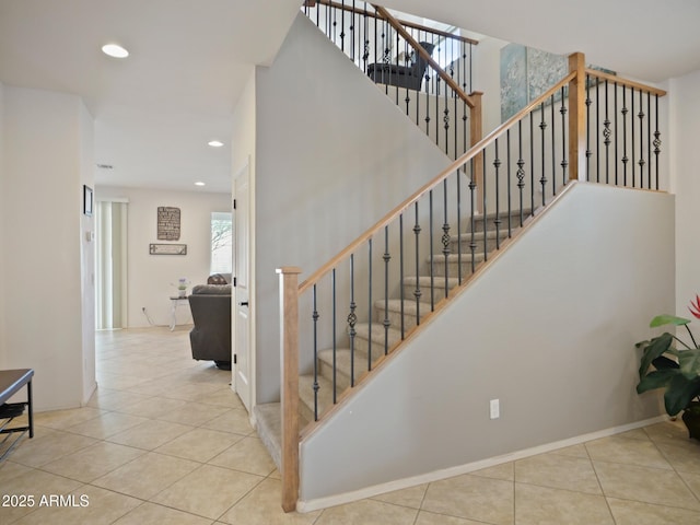 stairs with tile patterned flooring and a high ceiling