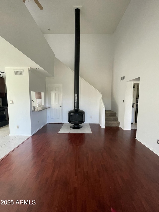 unfurnished living room featuring a towering ceiling, light hardwood / wood-style floors, and ceiling fan