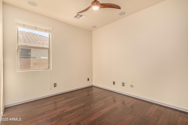 spare room featuring baseboards, ceiling fan, visible vents, and dark wood-style flooring