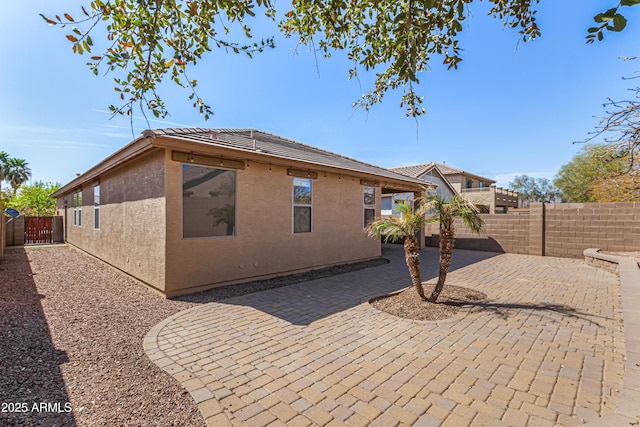 rear view of property with a patio, a fenced backyard, a tiled roof, and stucco siding