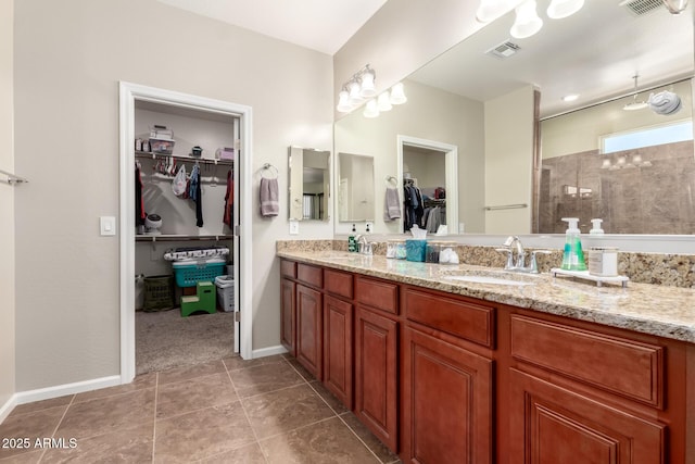 13123 W Cottontail Ln, Peoria, AZ 85383 - full bath with a tile shower, double vanity, a walk in closet, baseboards, and tile patterned flooring