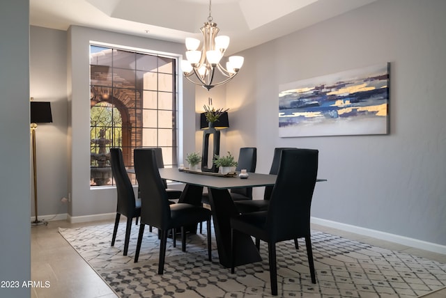 dining space featuring an inviting chandelier, a tray ceiling, and light tile patterned flooring